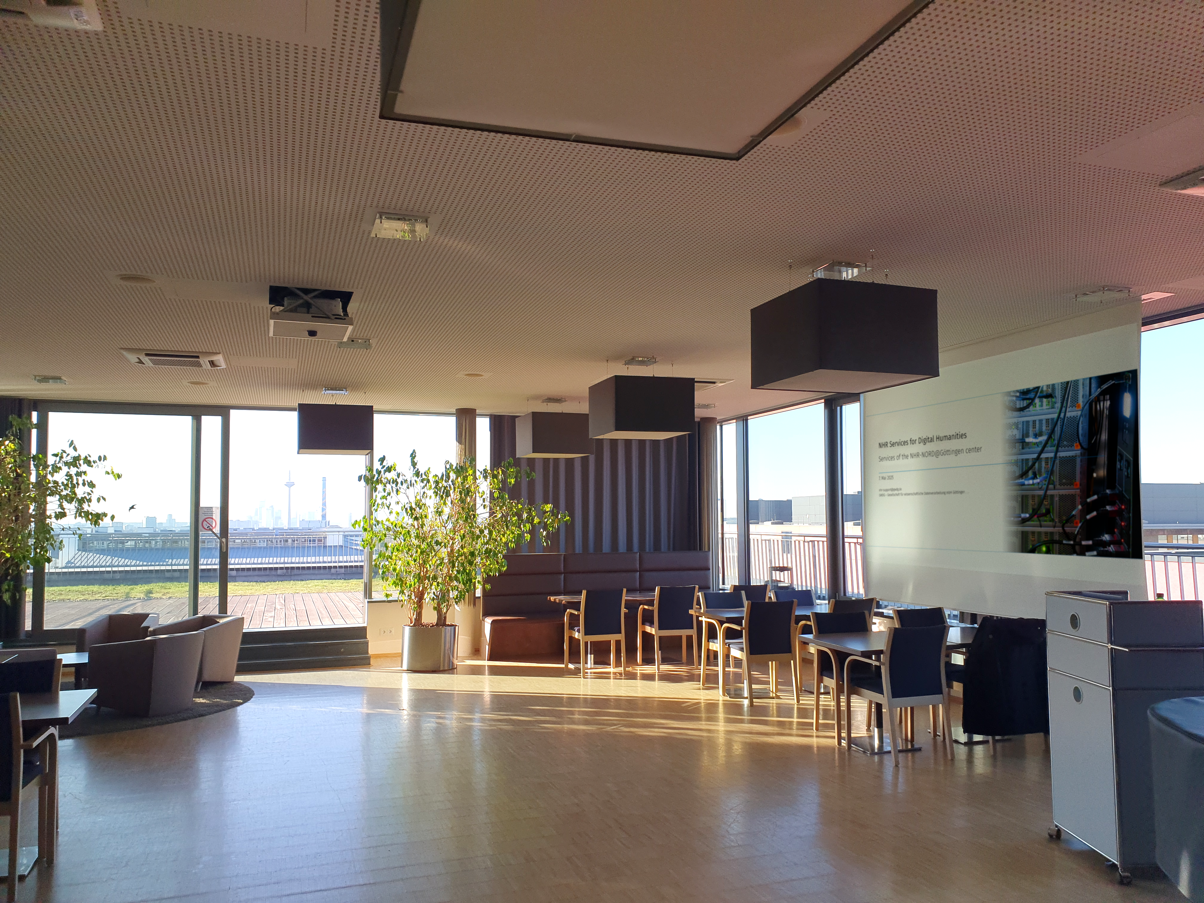 This is a meeting room with some comfortable chairs and a window out to a nice skyline. The right hand side has a presenter screen that is showing the slides of the NHR roadshow.